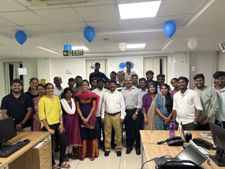 Team group photo in the office, decorated with blue and white balloons
