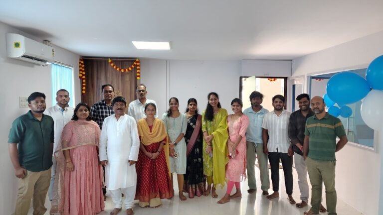 Team in traditional dress at the office pooja, with marigold garlands on the door